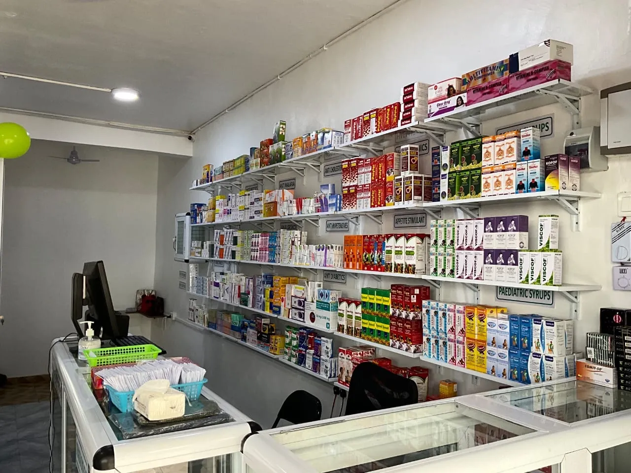 Neatly labelled shelves of medicines inside DenRich Pharmacy, Koforidua